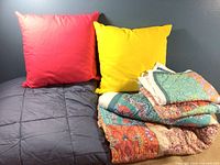 Blue quilted blanket with red and yellow pillows and colorful Boho quilt with detailed patterns.