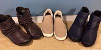 All three pairs of shoes: two Clarks booties and one OluKai loafers, arranged neatly showing front and sides.