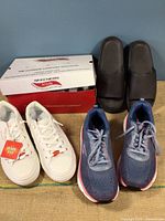 Front view of the three pairs of shoes with Skechers box in back including white new sneakers, used blue pair, and black Pink slip-ons