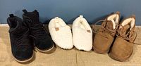 Front view of three pairs: black UGG short boots, white fuzzy slippers, and light brown UGG short boots showing outer appearance and style.