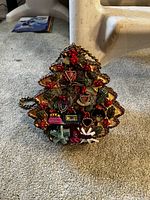 Front view of Christmas tree-shaped purse showing intricate hand-beaded decorations and embellishments including leaves, berries, and small handbags.