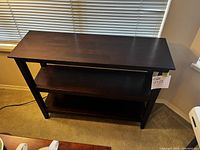 Front view of dark brown wooden 3-tier shelf unit, angled to show overall structure and moderate lighting.