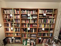 Full view of three wooden bookshelves arranged side-by-side, filled with books to show scale and shelf size.