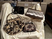 Four vintage beaded clutches and purses displayed on a cream satin-like cloth, showing overall lot contents and variety.