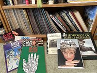 Shelf of books and magazines featuring Man Myth and Magic magazines, The World of Robert Bateman book, People magazine, and other titles.