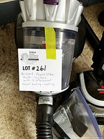 Close-up of the Bissell Power Lifter vacuum's multi-cyclonic clear dust canister with a label showing lot information and mention of 3 attachments, condition working.