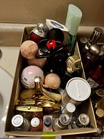 Top view of box with assorted perfumes, bath bombs, nail polish, blush, and cosmetic items.