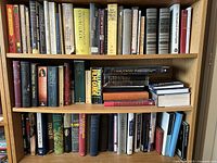 Shelf showing rows of various hardback books including Halliwell's Film Guide, Oscar Wilde's works, biographies, and scientific titles.