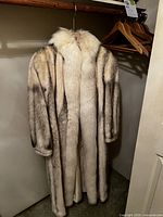 Full-length view of mink coat hanging on wooden rod in closet