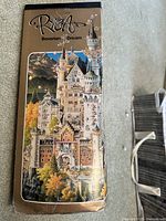 Front view of the tall puzzle box showing the "Bavarian Dream" puzzle illustration featuring a Bavarian castle and landscape in cartoon style by Michael Ryba.
