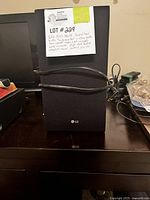 Front view of LG sound bar with label describing lot details including 300 watt sound bar with subwoofer, Bluetooth rear speaker ready (not included) and remote, high res audio, adaptive sound control, wireless.