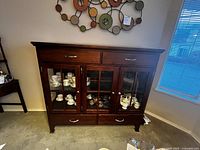 Front view of solid wood china cabinet showing glass panel doors, drawers, and top surface.