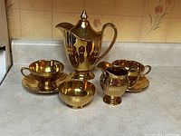 Full set including coffee pot, 2 teacups and saucers, sugar bowl and creamer on countertop
