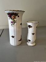 Photo shows the two Royal Albert Old Country Roses vases side by side on a flat surface with visible floral patterns and gold trim.