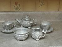 Full set on countertop showing teapot, two cups with saucers, creamer, and sugar bowl with lustre ware shell pattern and pearly iridescent finish