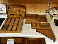 Photo showing full set of bamboo drawer organizers laid out on countertop along with wooden wall organizer at back