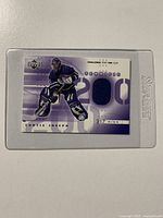 Front view of the Curtis Joseph hockey card showing the image of the goalie and embedded piece of dark blue jersey fabric.