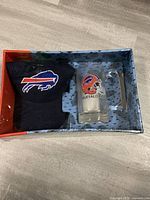 Top view of the gift set box showing the navy blue Buffalo Bills hat and the clear glass Buffalo Bills mug inside the packaging.