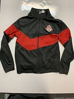 Front view of black and red Toronto FC youth jacket with Toronto FC logo on chest