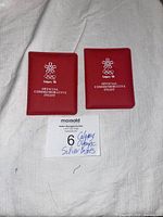 Two red cases side by side, each embossed with Calgary '88 Olympic logo and Official Commemorative Ingot text.