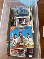 Clear box filled with assorted NHL hockey cards, including a visible 'NHL Superstar Rookies' box and several loose rookie cards on top.