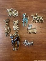 Top view showing all nine vintage cat and dog brooches arranged on a wooden surface.