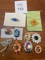 Full overview of all 10 vintage floral brooches displayed on a table
