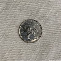 Single close-up of a 1973 Canadian 25 cent RCMP anniversary quarter showing detailed design of mounted Mountie, denomination and dates 1873-1973.