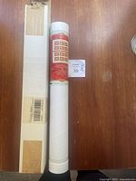 Rolled stamp sheet in protective cylindrical tube with original packaging visible.