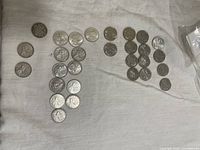 Wide view of assorted Canadian quarters laid out on fabric surface showing various commemorative designs.