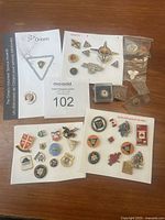 Multiple Canadian volunteer service and commemorative pins arranged on a wooden surface, showing variety of designs including Ontario Volunteer Service Awards and other Canadian symbols.