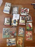 Assorted NFL football trading cards laid out on a wooden table showing multiple players and card brands.