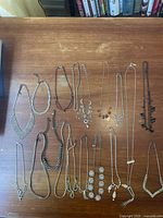 17 rhinestone necklaces laid out on a wooden surface, displaying full variety and lengths of each necklace.