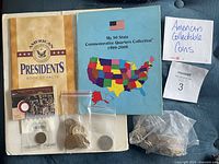 Photo showing American Presidents Book of Facts booklet, 50 State Commemorative Quarters Collection folder, and bags of assorted American collectible coins including quarters and half-dollar.