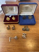 Six pairs of vintage Government of Ontario cufflinks displayed on wooden surface with two original presentation boxes.