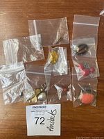 Photo showing nine small vintage silver pendants in individual plastic bags on a wood surface