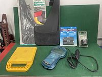 Lot contents on green surface including mud flaps, code reader, adapters and protective case.