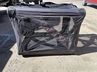 Front mesh window view of the collapsible dog kennel showing zipper and black fabric sides