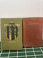 Front covers of two early 1900s hardcover books, 'The Pines of Lory' and 'Poems of R. Browning'.