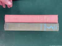 Top edges and spines of two hardcover books, one pink and one gray/green.