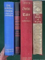 Four vintage hardcover books lined up vertically showing spines: The Moving Finger, The Case of the Backward Mule, Seven Gothic Tales, The Works of Kipling.