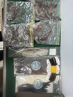 Plastic bags of assorted feathers including a large white feather and other natural colors with some Metz brand packaging