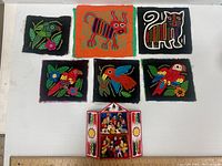 Six colorful Guatemalan embroidered tapestries featuring animals and birds, along with a small folk art cathedral diorama.