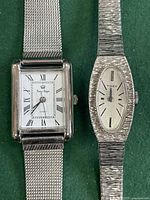 Close-up of square and oval vintage silver-tone watches showing faces and band texture.