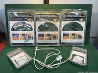 Three packaged Hampton Bay 18 ft green rope light kits with connectors, cords visible.