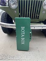 Closed green BOTA BOX branded folding picnic table with handle for carrying.