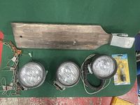 Image showing a vintage wooden fish board and three vintage round automotive-style lights with wired attachments, plus an unopened keychain light.