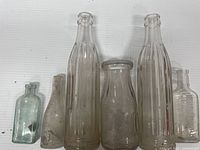 Overview of six vintage glass bottles of varying sizes and shapes on a white background.