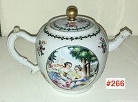 Front view of globular porcelain teapot with famille rose pastoral scene in oval cartouche, brass finial on lid, white ceramic body.