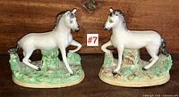 Front view of both white glazed horse figures on green and brown bases